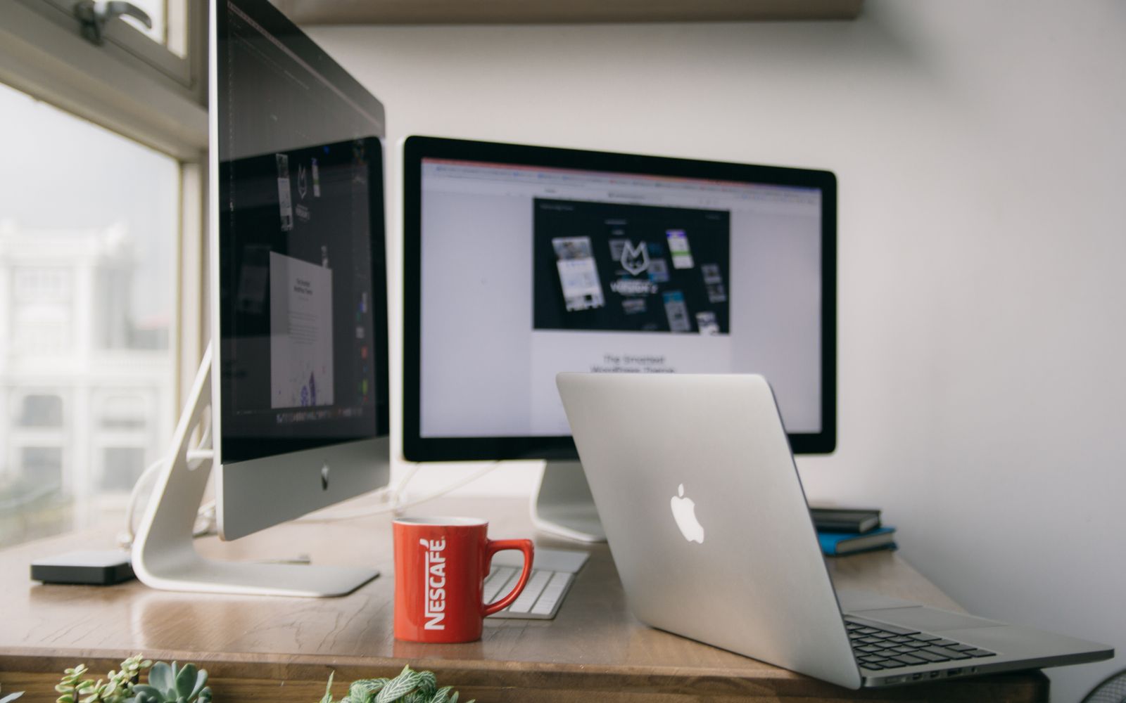 A bright modern office setup with computers and a mug on a desk.