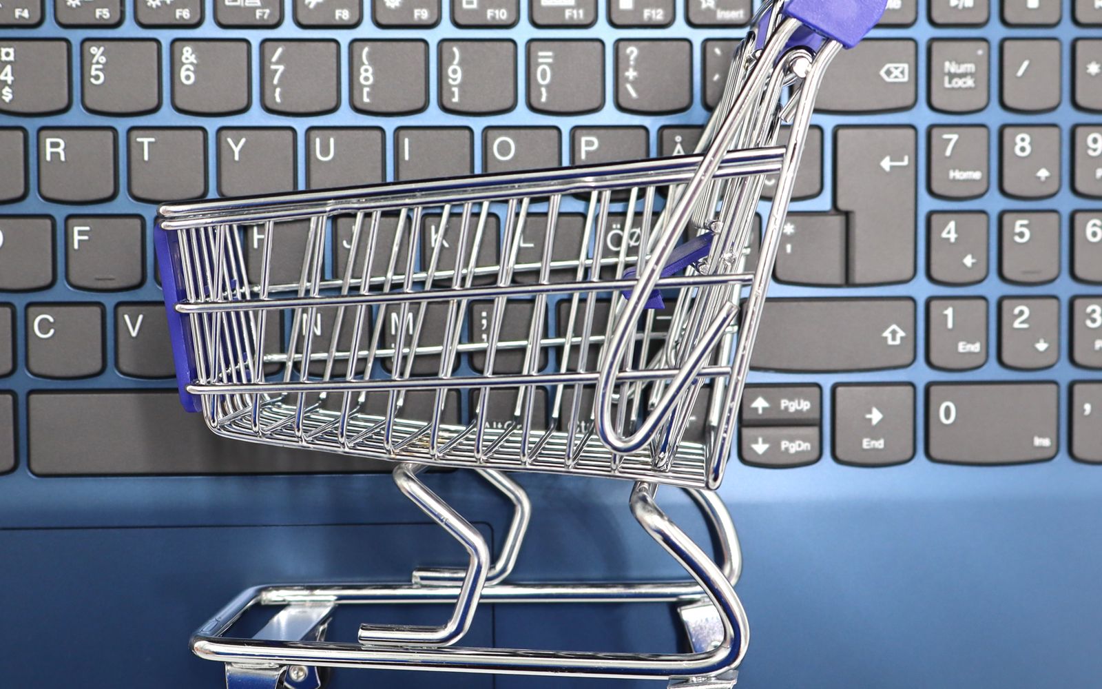 A miniature shopping cart placed on a laptop keyboard symbolizing online shopping and e-commerce.