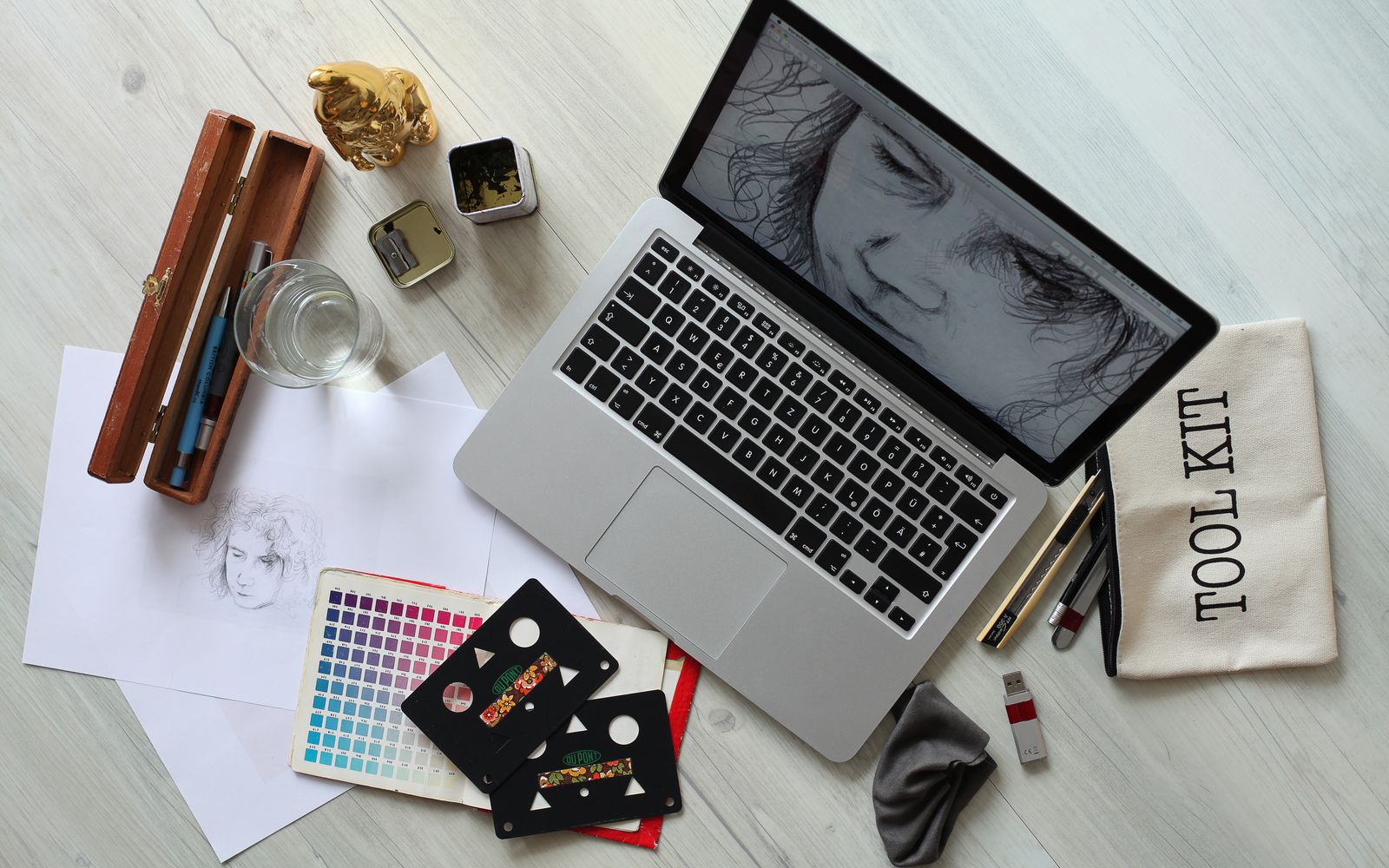 Top view of a creative workspace with a laptop, sketch supplies, and color palette.