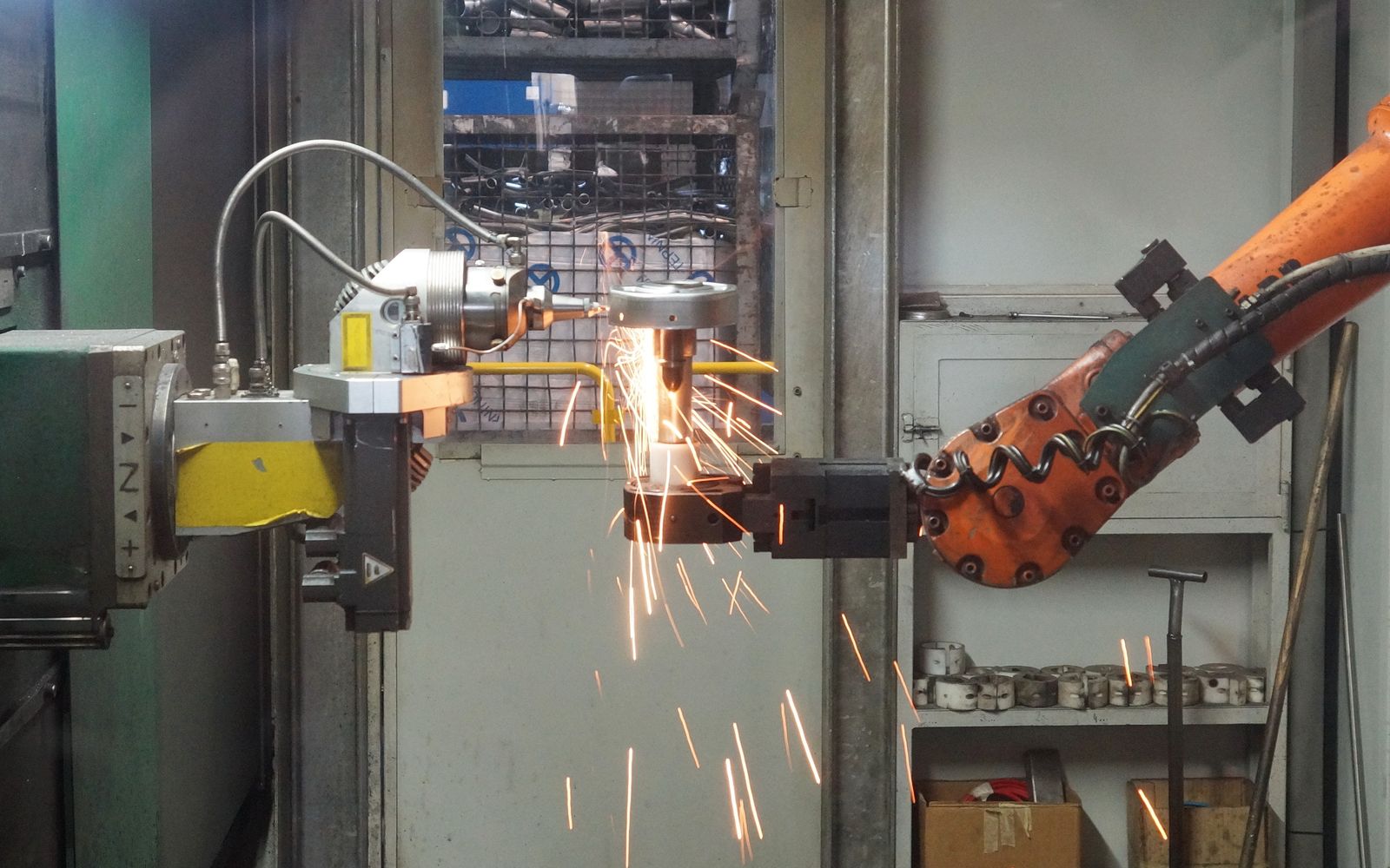 A robotic arm welding in an industrial setting, emitting bright sparks.