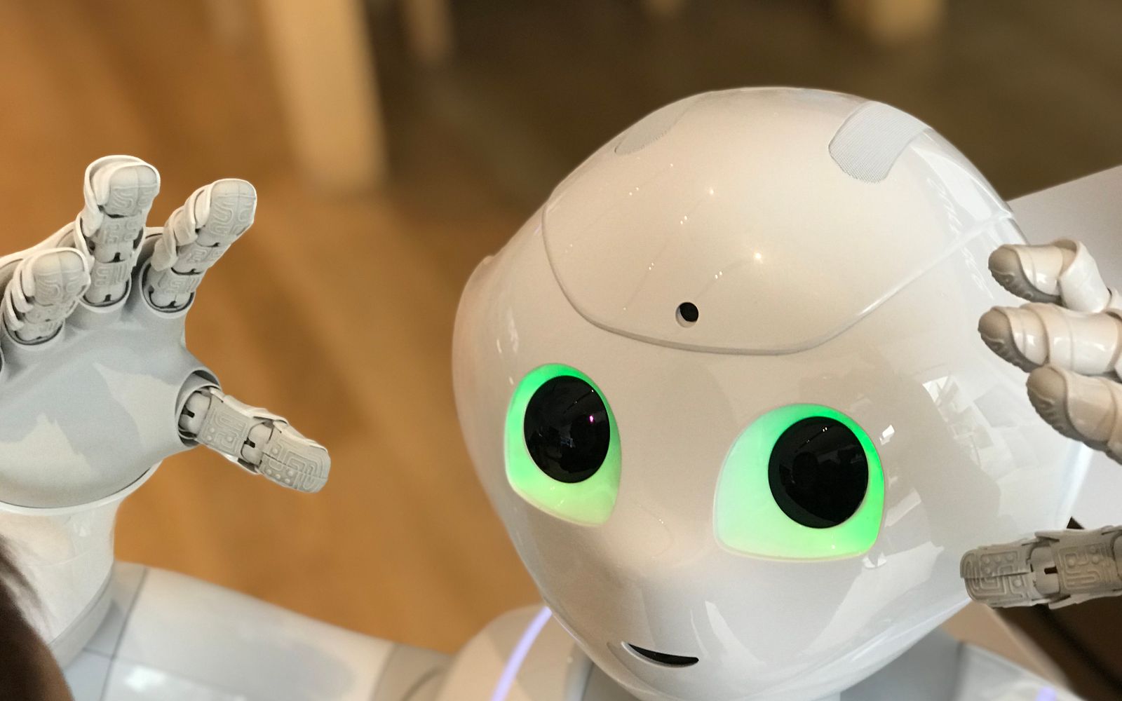 A futuristic humanoid robot with glowing green eyes in a modern setting.
