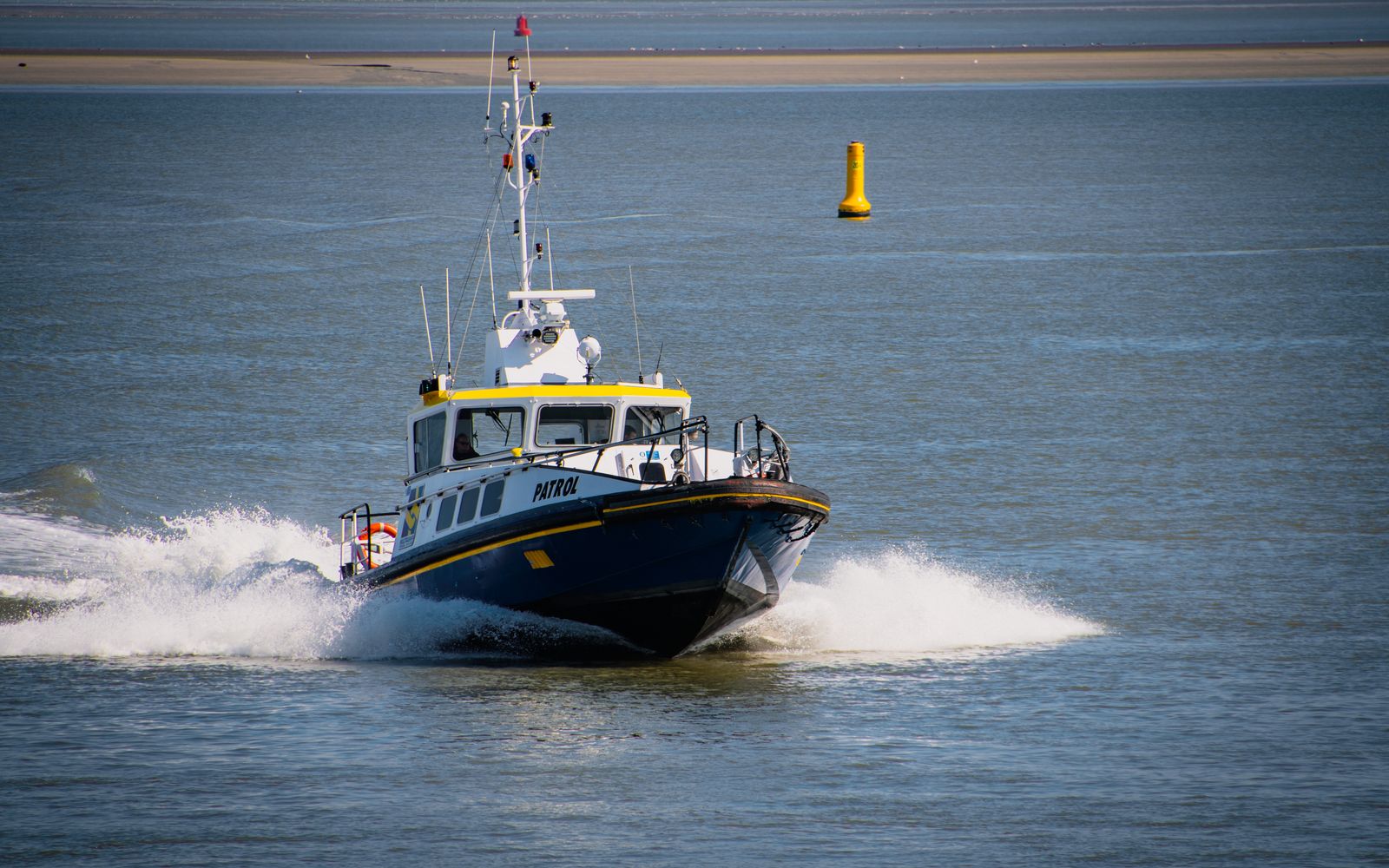 Patrol boat speeding through open sea water, creating splashes as it navigates.