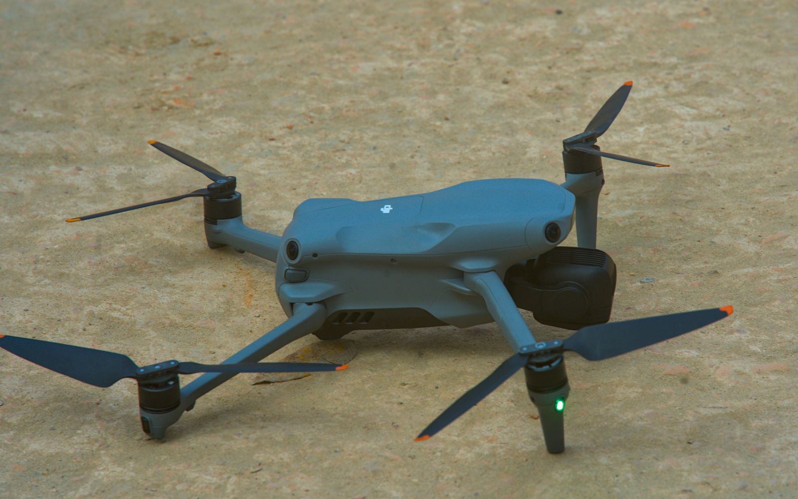High-tech quadcopter drone resting on gravel ground, ready for flight operations.