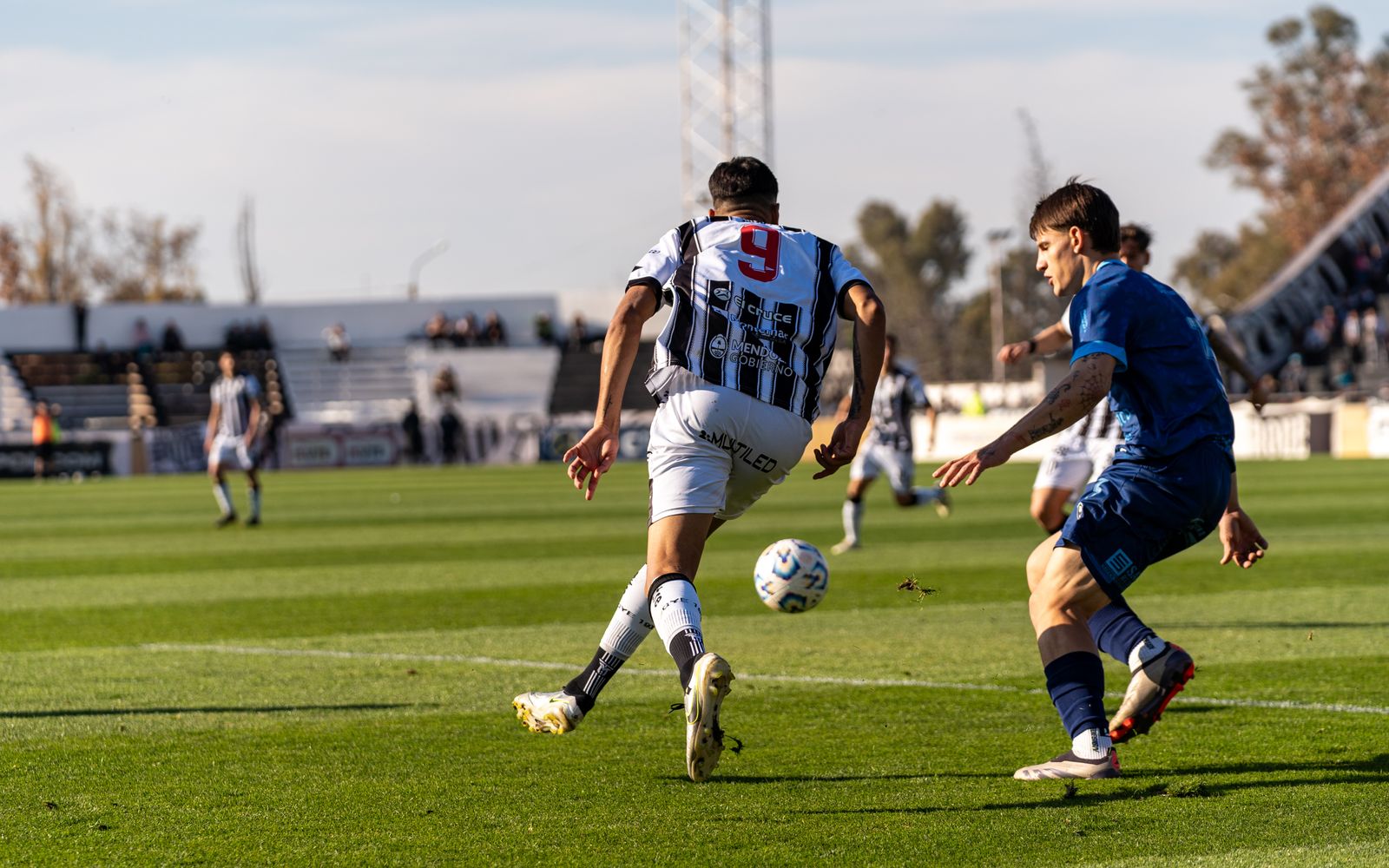 Players in action on the soccer field during an outdoor match under the bright sun.