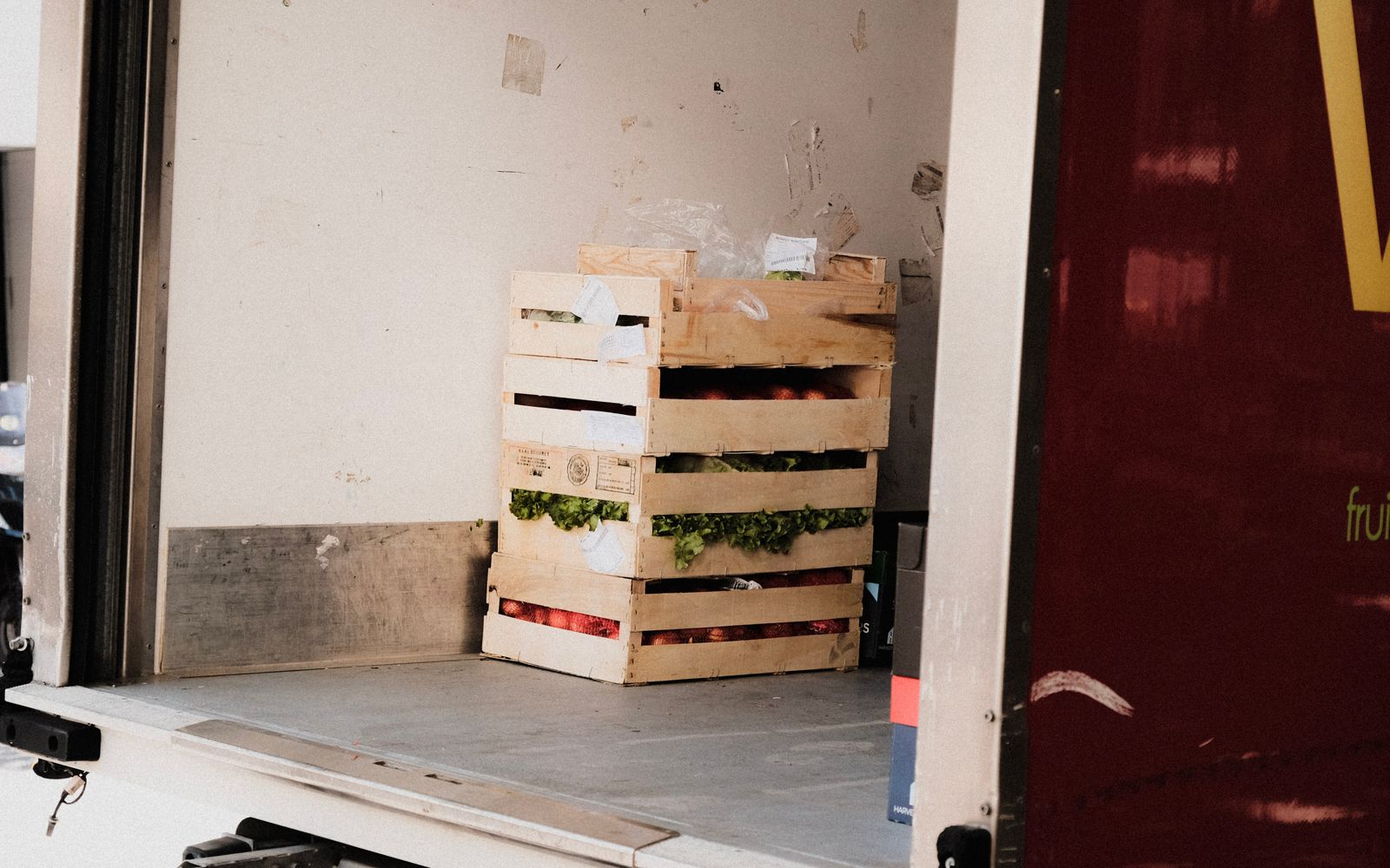 A wooden crate with fresh vegetables loaded inside a delivery truck, ready for transportation.