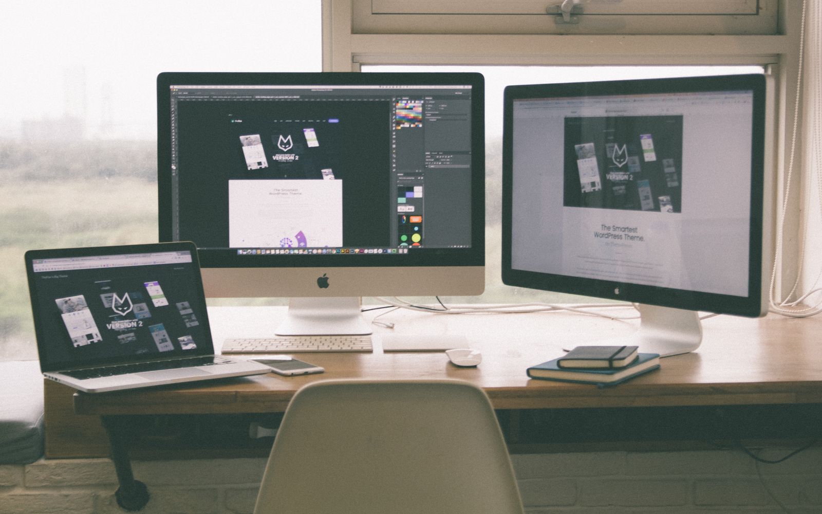 Stylish and efficient workspace with multiple monitors, laptop, and smartphone, showcasing a web design project.
